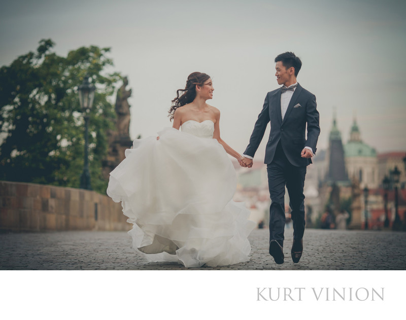 Happy wedding couple running across Charles Bridge