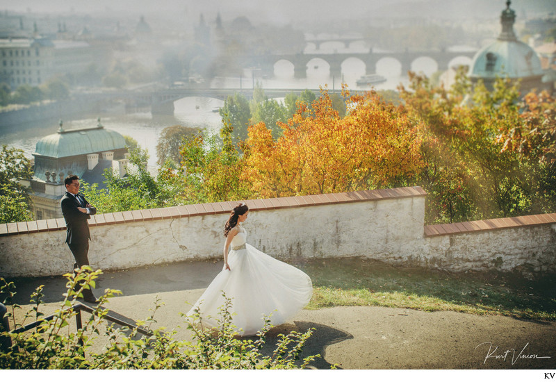 twirling bride as groom watches above Prague 