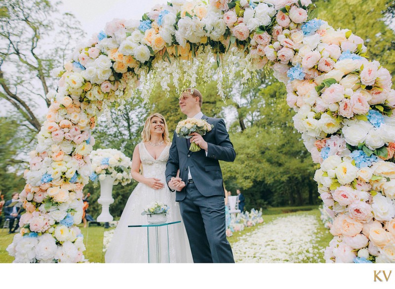 The happy Anna and Sergio under the floral arch