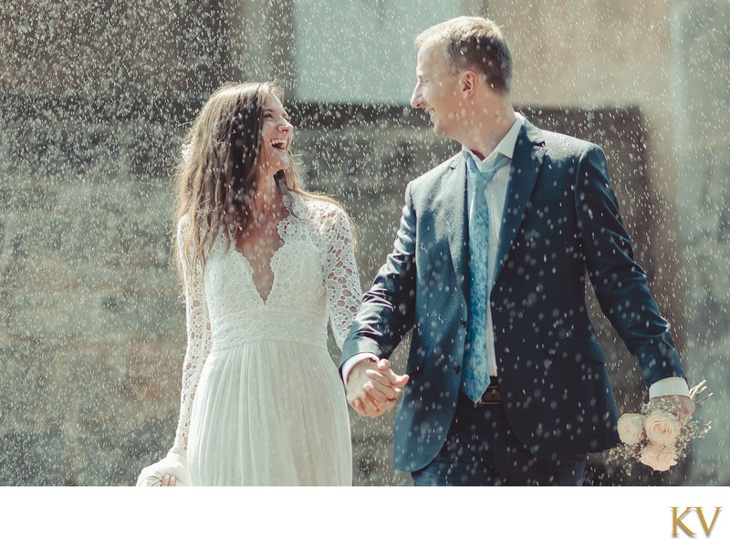 Newlweds walking through sprinkler at Prague Castle