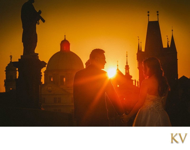 Hong Kong couple walking across Charles Bridge sunrise