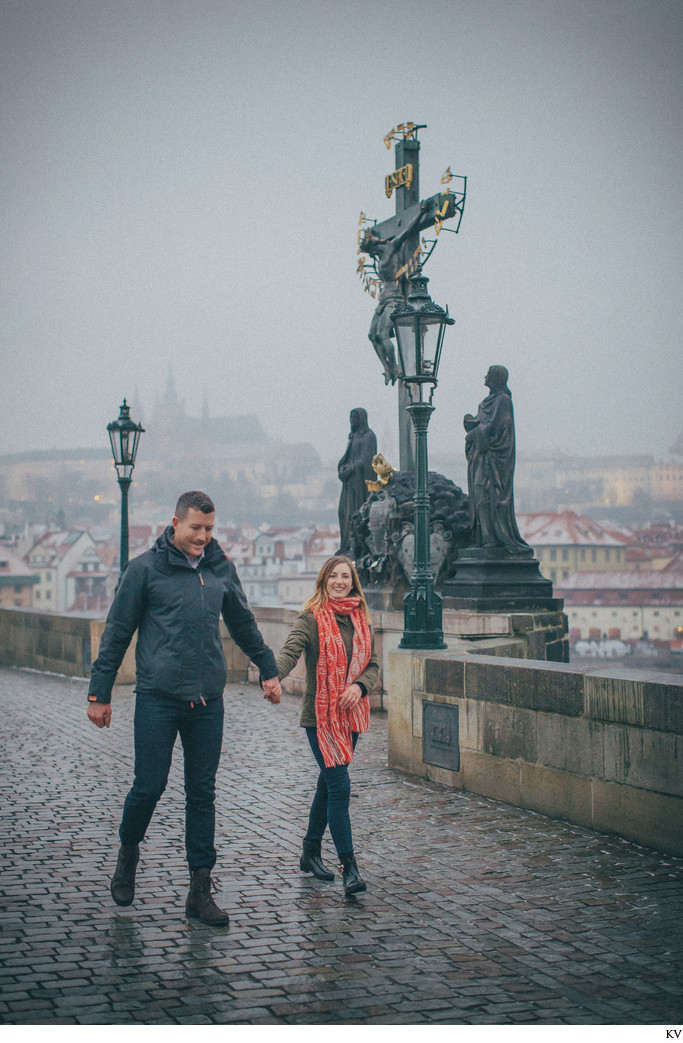 newly engaged happily walking across the Charles Bridge