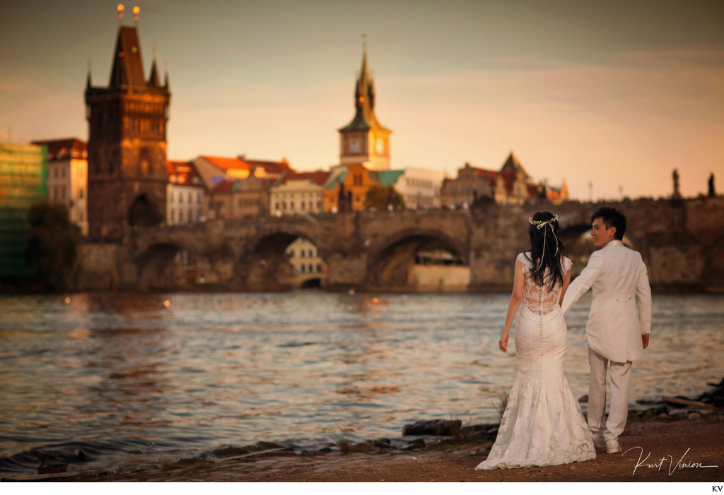 Newlyweds walking along the riverside at sunset