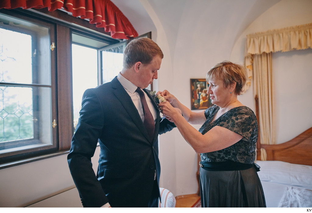 mother places boutonniere on groom