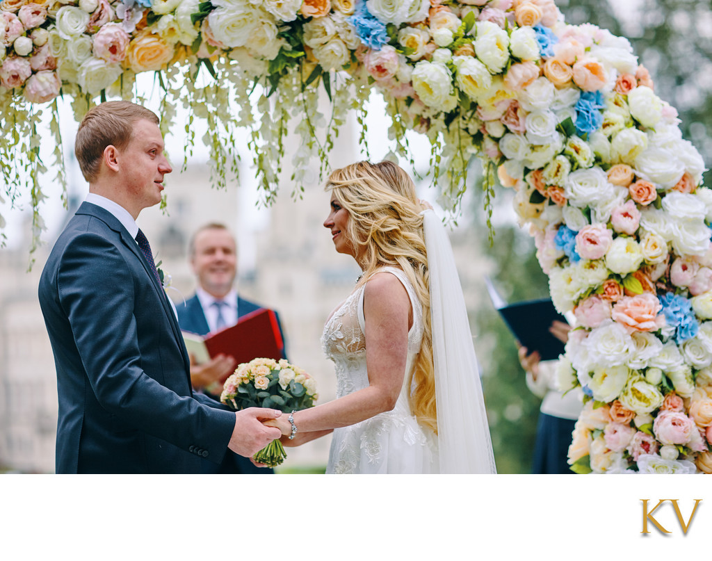 holding hands under the floral arch