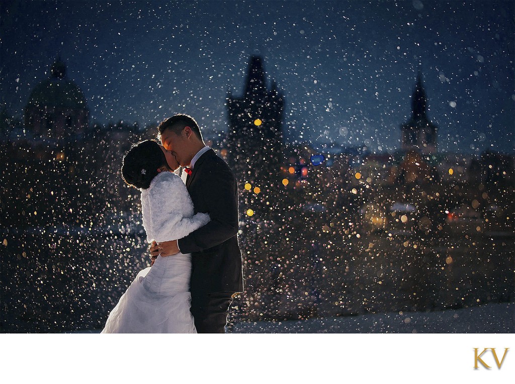 Newlyweds kissing in snowstorm Prague