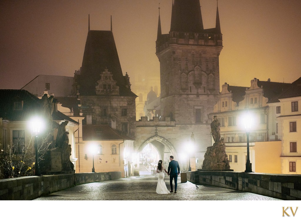 Strolling hand in hand on the foggy Charles Bridge at night