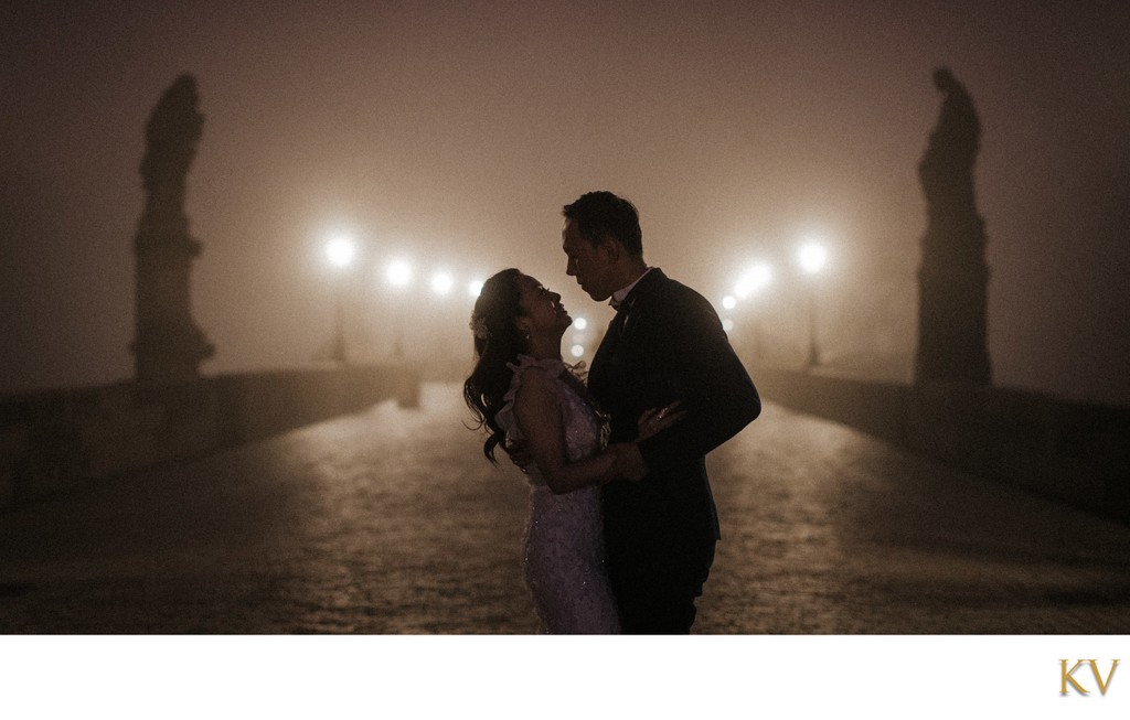 Lovers in the fog atop the Charles Bridge at night