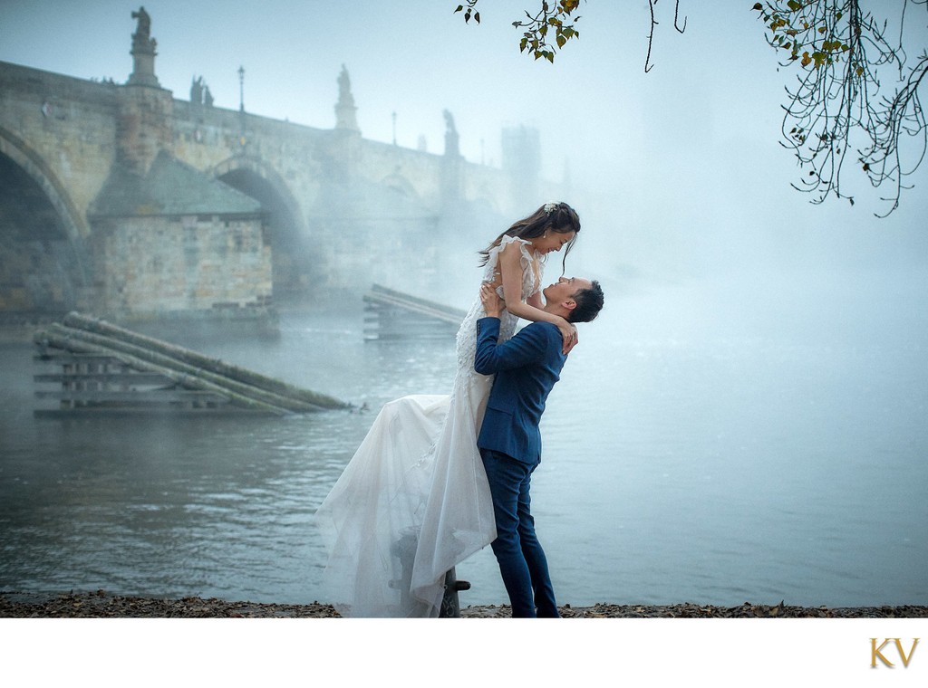 picking up his bride near foggy Charles Bridge