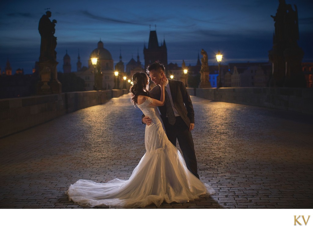 embracing atop the Charles Bridge at night