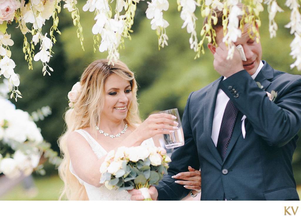 bride gives water to teary eyed groom during ceremony