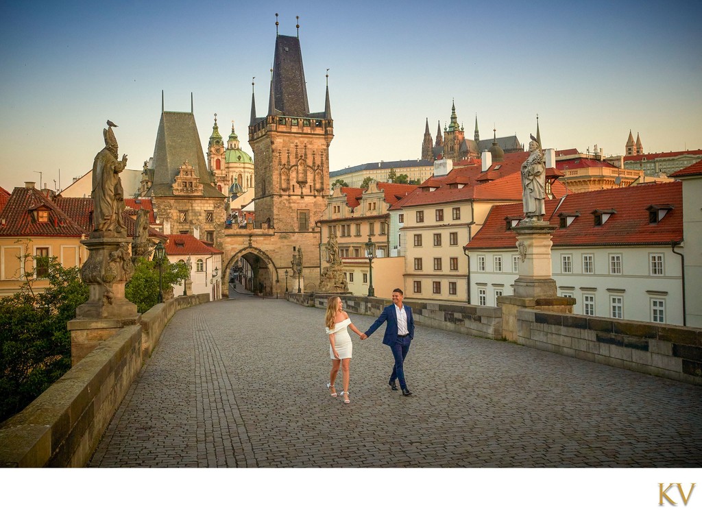 walking hand-in-hand across Charles Bridge at sunrise