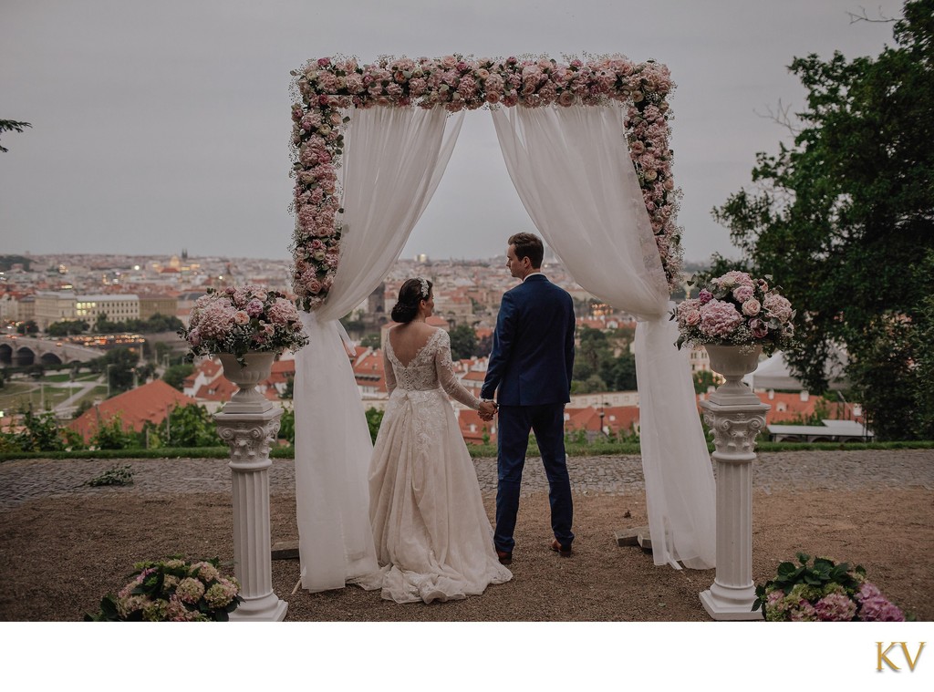 Newlyweds at dusk overlooking Prague under the floral arch