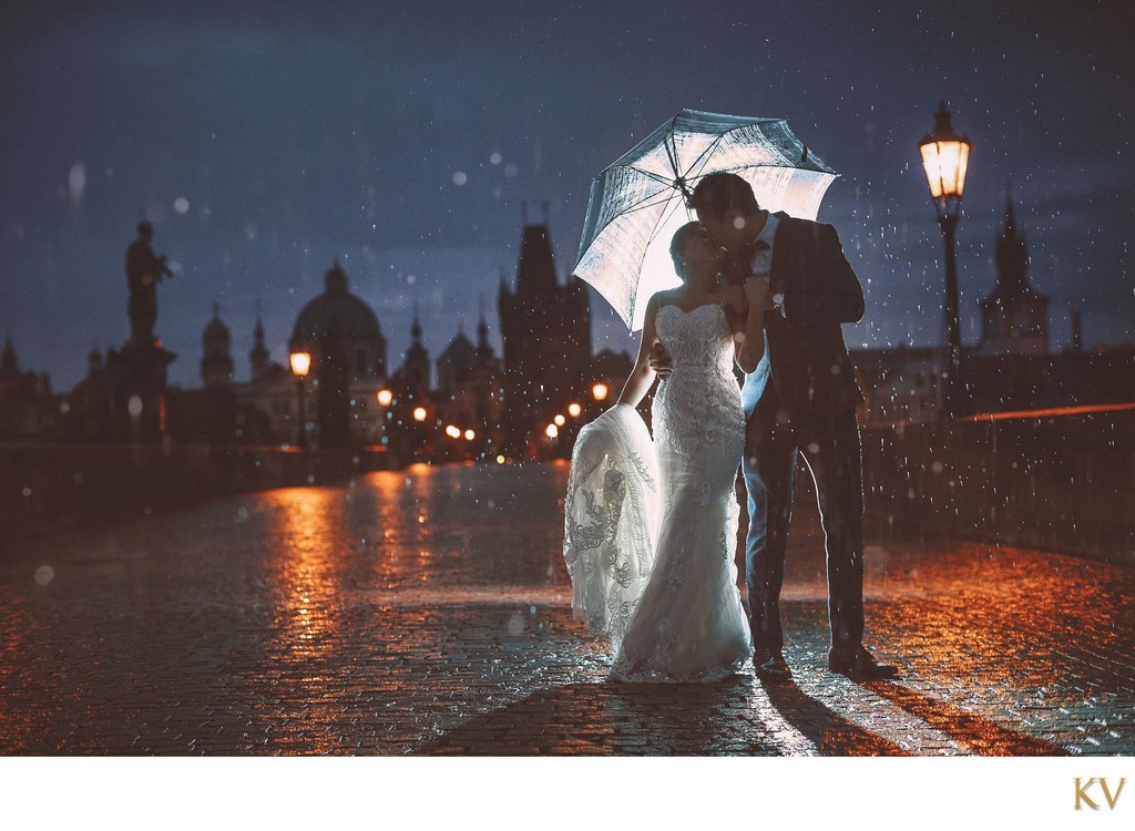 rain soaked bride & groom atop Charles Bridge at night