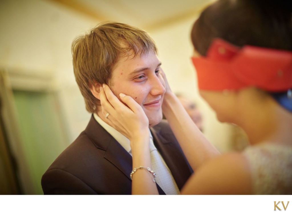 blindfolded bride touches face of groom