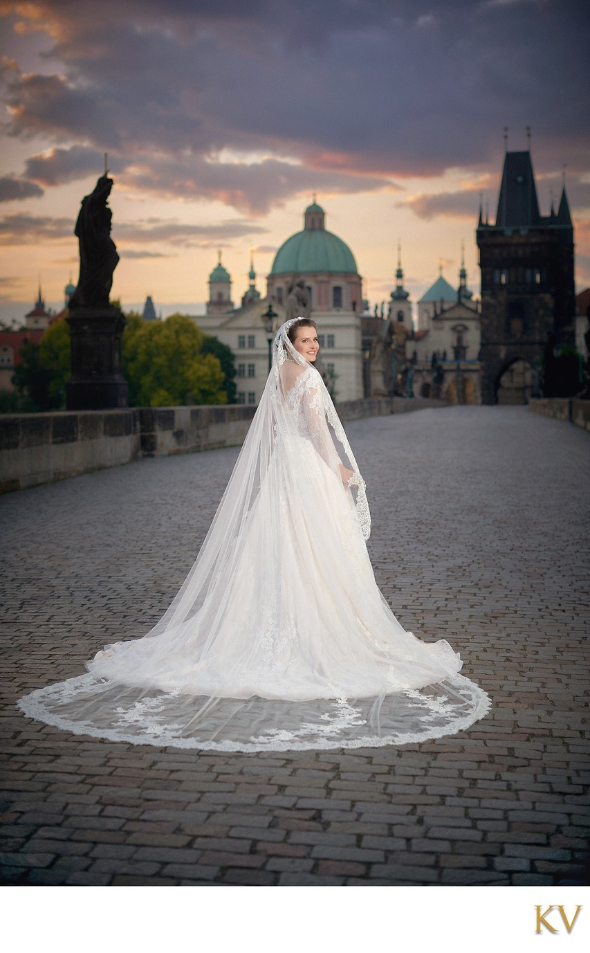 Adele posing in wedding dress on Charles Bridge at sunrise