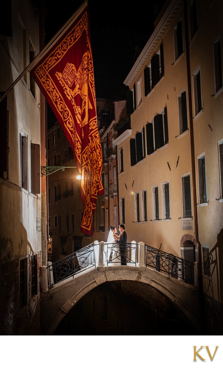 Couple enjoy the canals of Venice under Standard of Saint Mark