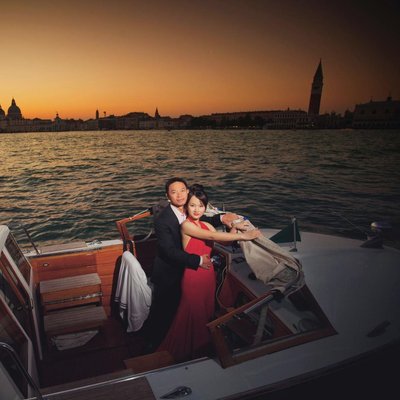 Thai couple in boat enjoying sunset over Venice