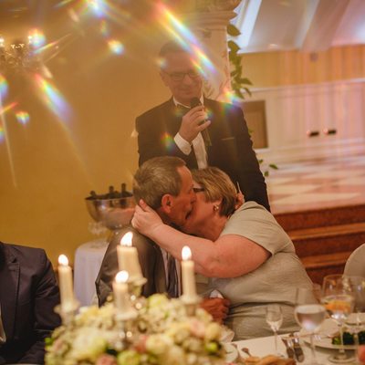 The brides parents kiss at the wedding dinner