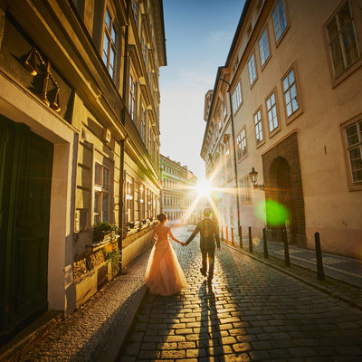 holding hands walking in sunshine historic Prague