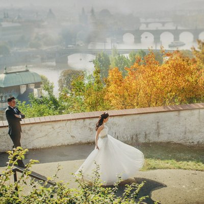 twirling bride as groom watches above Prague 