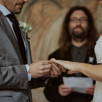 placing the wedding band on his brides finger