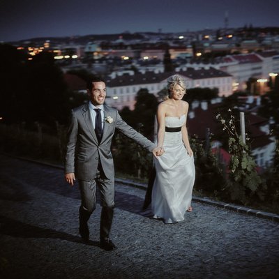 Excited bride led by groom into vineyards above Prague