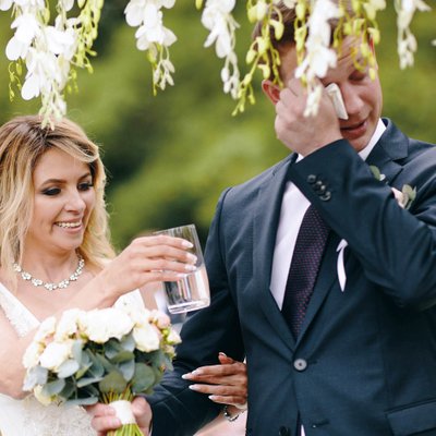 bride gives water to teary eyed groom during ceremony