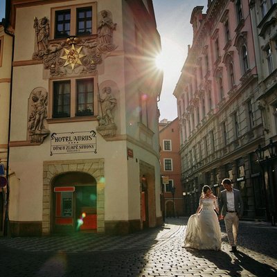 sun flare leads a couple in the Old Town of Prague