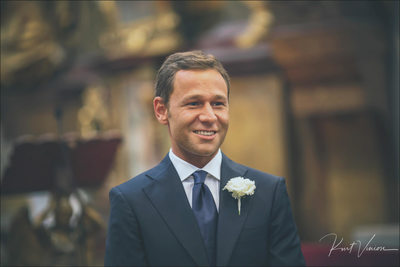 smiling groom waiting at the alter 