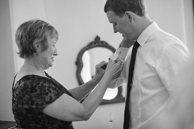 The mother of the groom assists with cuff links