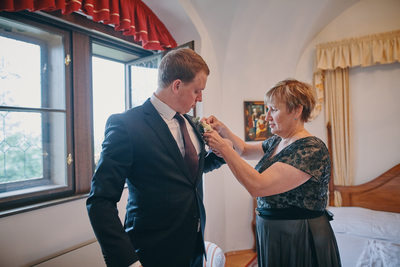 mother places boutonniere on groom