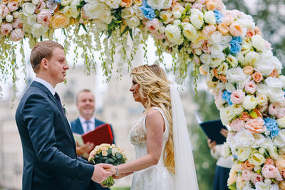 holding hands under the floral arch