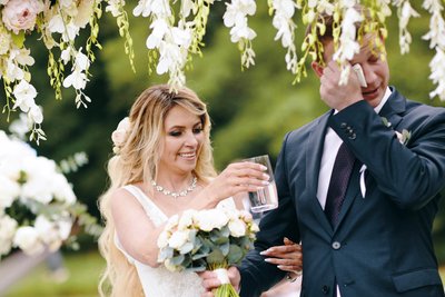 bride gives water to teary eyed groom during ceremony