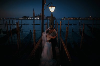 Venice bride & groom embracing near gondola at night