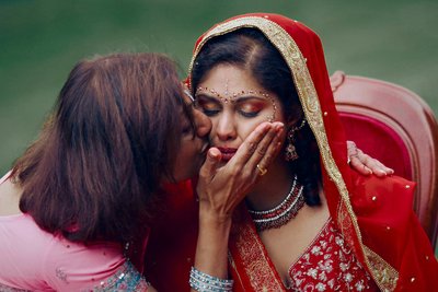 tearful Indian bride caressed by her mother