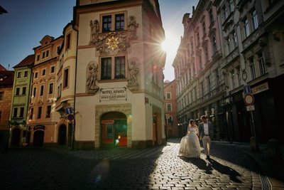 sun flare leads a couple in the Old Town of Prague
