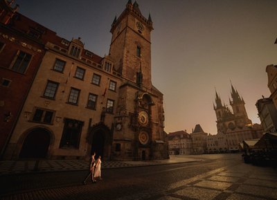 couple walk through Prague's historic Old Town Square at sunrise