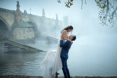 picking up his bride near foggy Charles Bridge