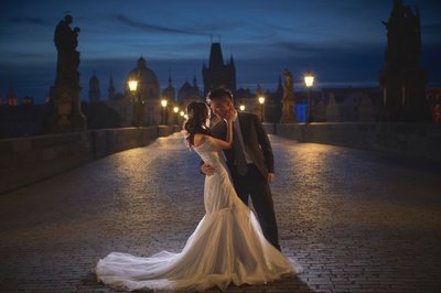 embracing atop the Charles Bridge at night