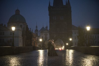 embracing in the solitude of the Charles Bridge at night