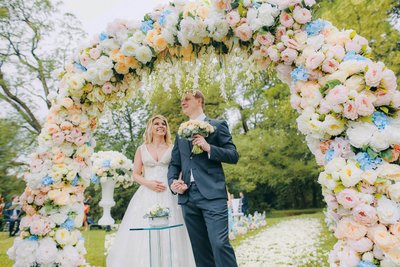 The happy Anna and Sergio under the floral arch