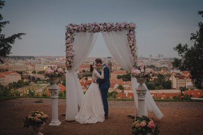 Newlyweds Embrace Above Prague Under Floral Arch