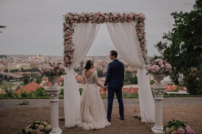 Newlyweds at dusk overlooking Prague under the floral arch