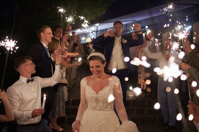 Wedding guests celebrate the bride and groom with sparklers