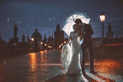 rain soaked bride & groom atop Charles Bridge at night