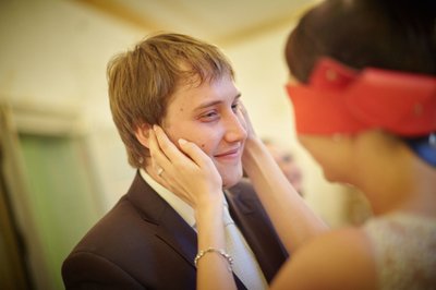 blindfolded bride touches face of groom