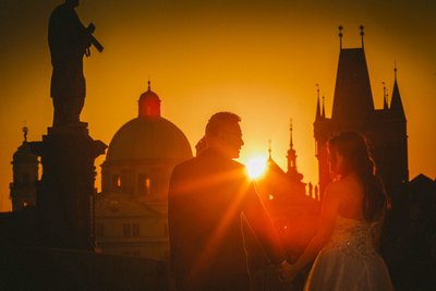 Hong Kong couple walking across Charles Bridge sunrise