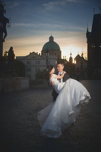 picking up his bride at sunrise atop Charles Bridge