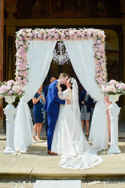 Newlyweds kiss under a chandelier at the Ledebour Garden in Prague